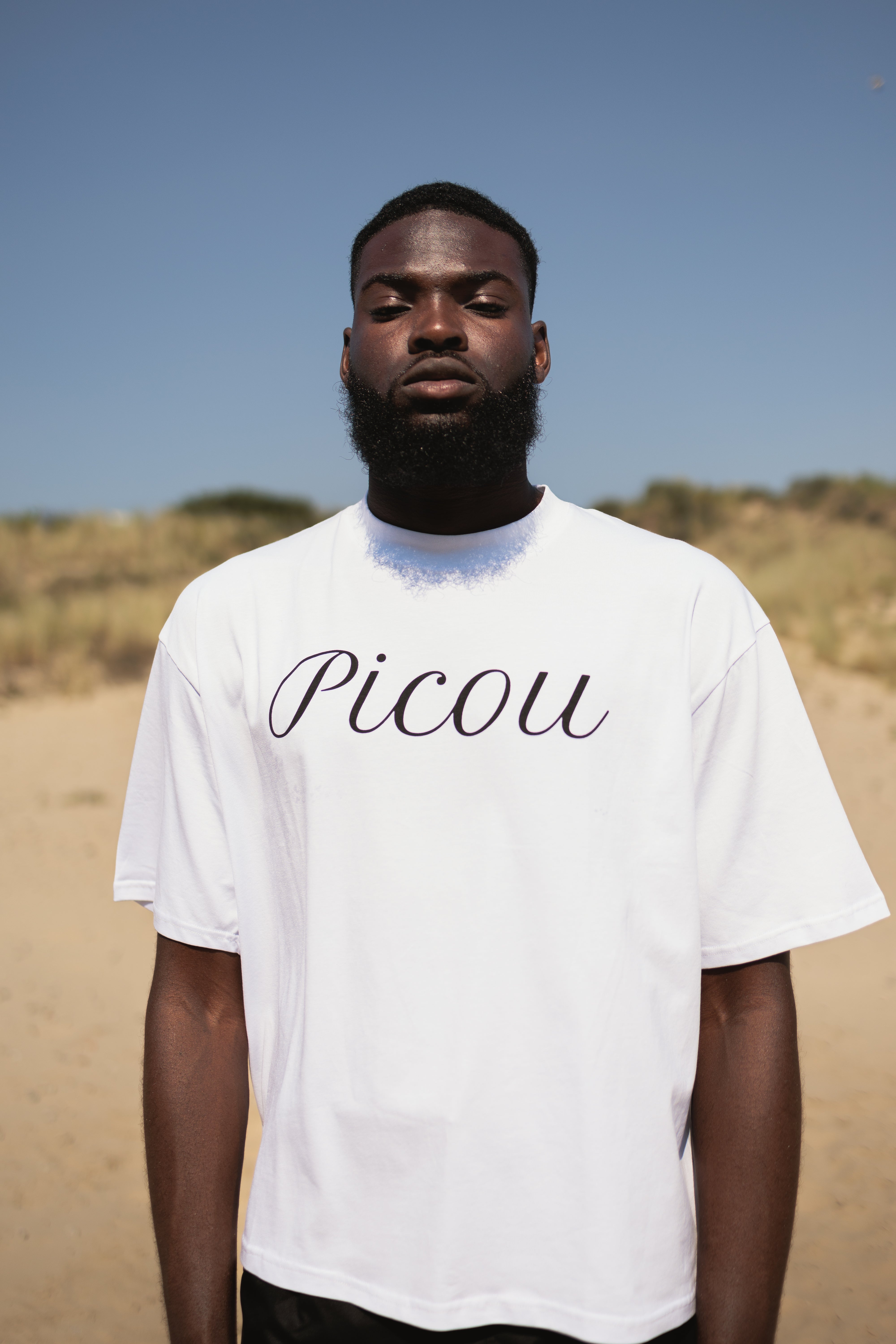 The Picou Cotton T-Shirt features the brand name elegantly written in cursive black letters across the front on a plain white background. A versatile and stylish addition to any fashion-forward wardrobe.