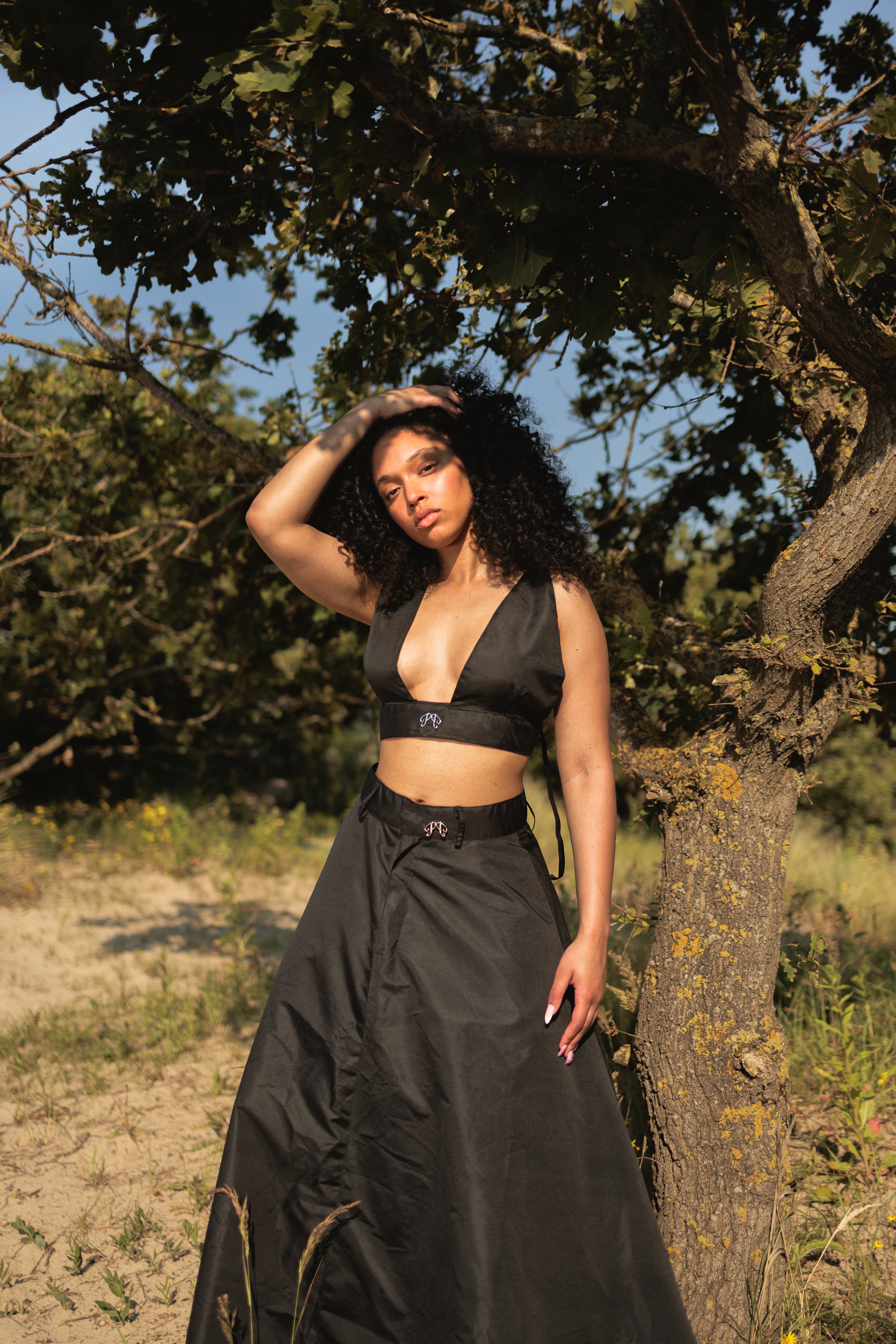 Picou nylon bralette in black: a luxurious piece featuring deep V-neck design with shoulder straps secured with silver buckle. At the front a center, metal logo element. High quality craftmanship