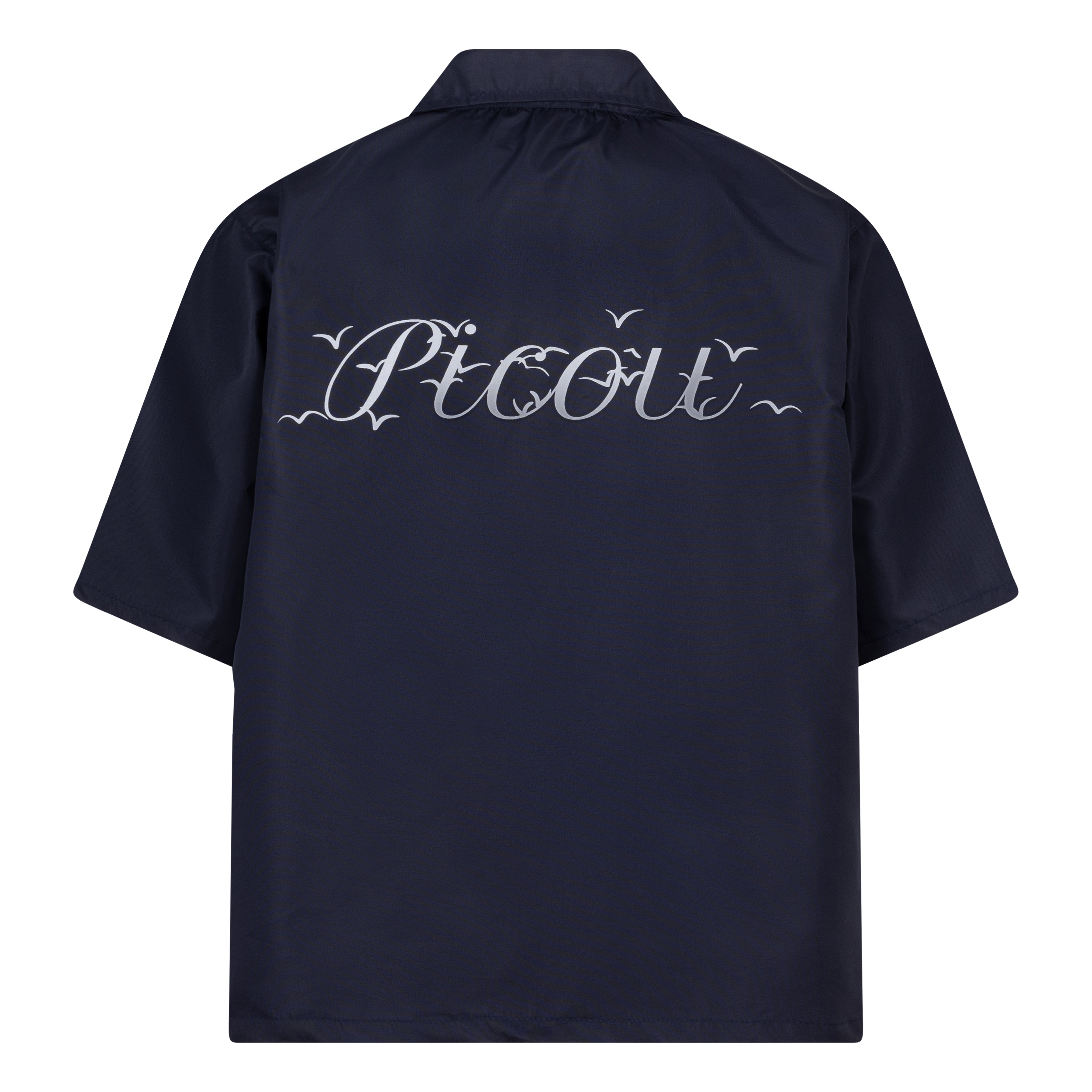 The Picou Nylon shirt in dark blue is a short-sleeve button-up with a notched collar and a front pocket on the left chest. The pocket features a small metal tag design with intertwined letters in silver. This casual shirt offers a relaxed fit and is crafted from lightweight fabric, ideal for fashion-forward individuals seeking quality.